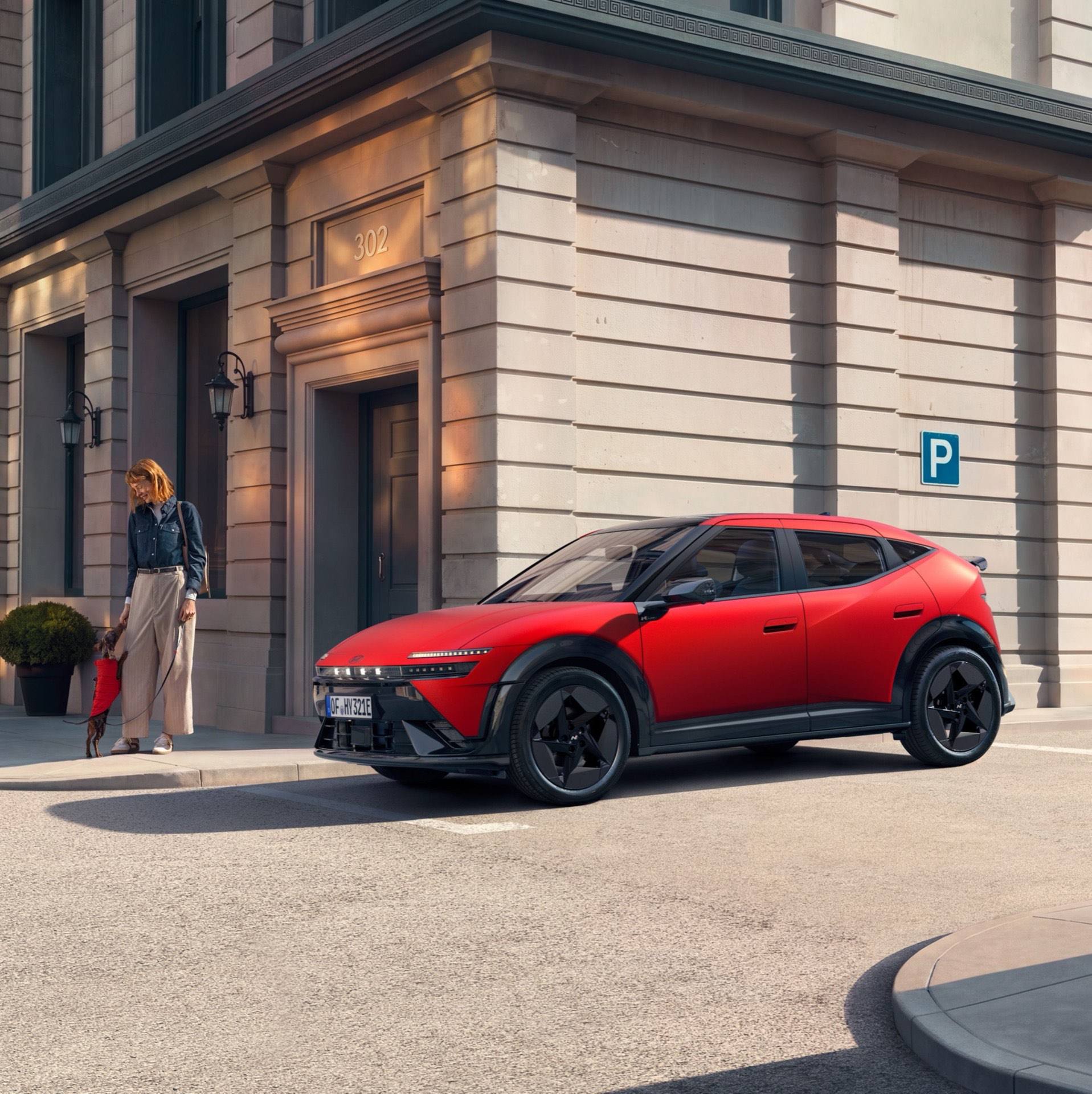 Hyundai IONIQ 3 EV parked on a city street with a woman and child standing next to it.