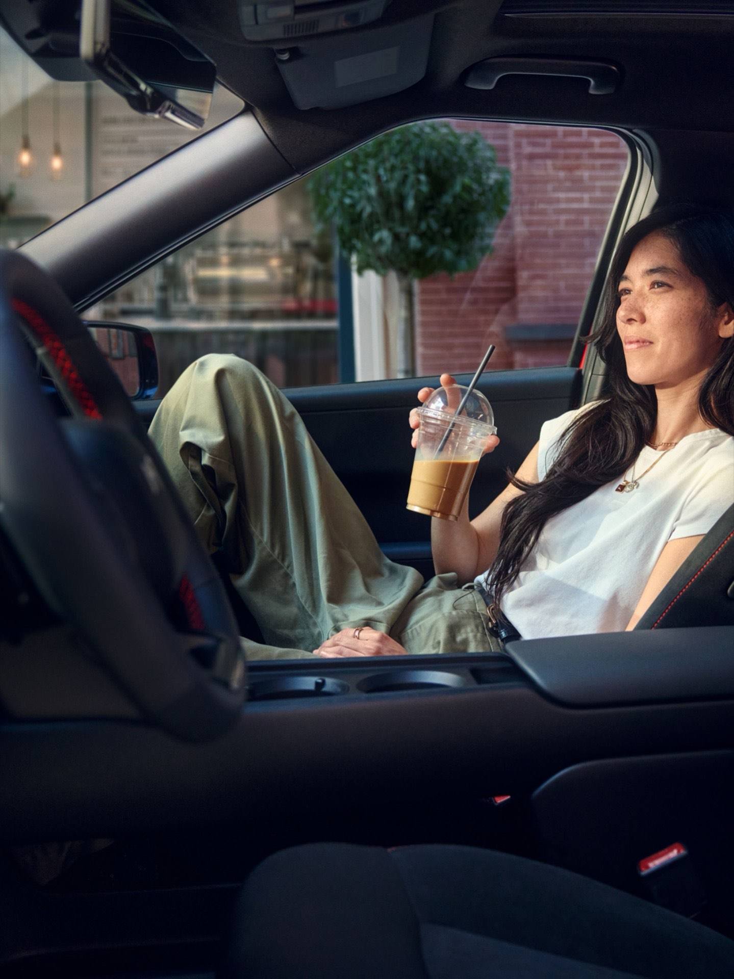 Interior view of a Hyundai IONIQ 3 showing a person seated in the front passenger seat, with the centre console and cup holders
