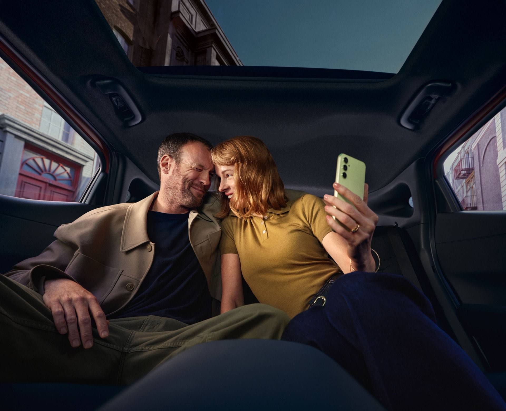 Interior of a Hyundai IONIQ 3 with black seats; two people relaxing in the rear seats.