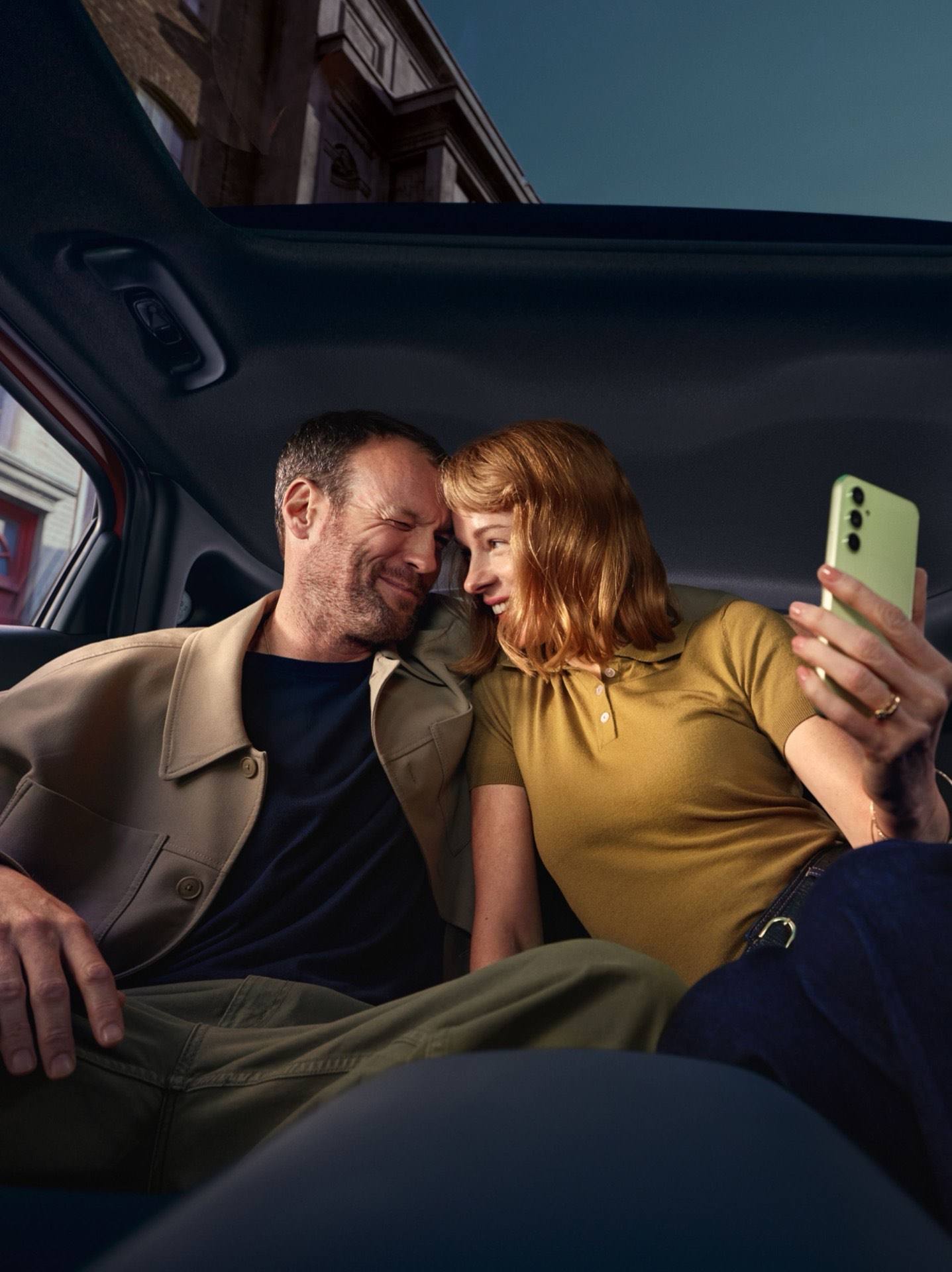 Interior of a Hyundai IONIQ 3 with black seats; two people relaxing in the rear seats.