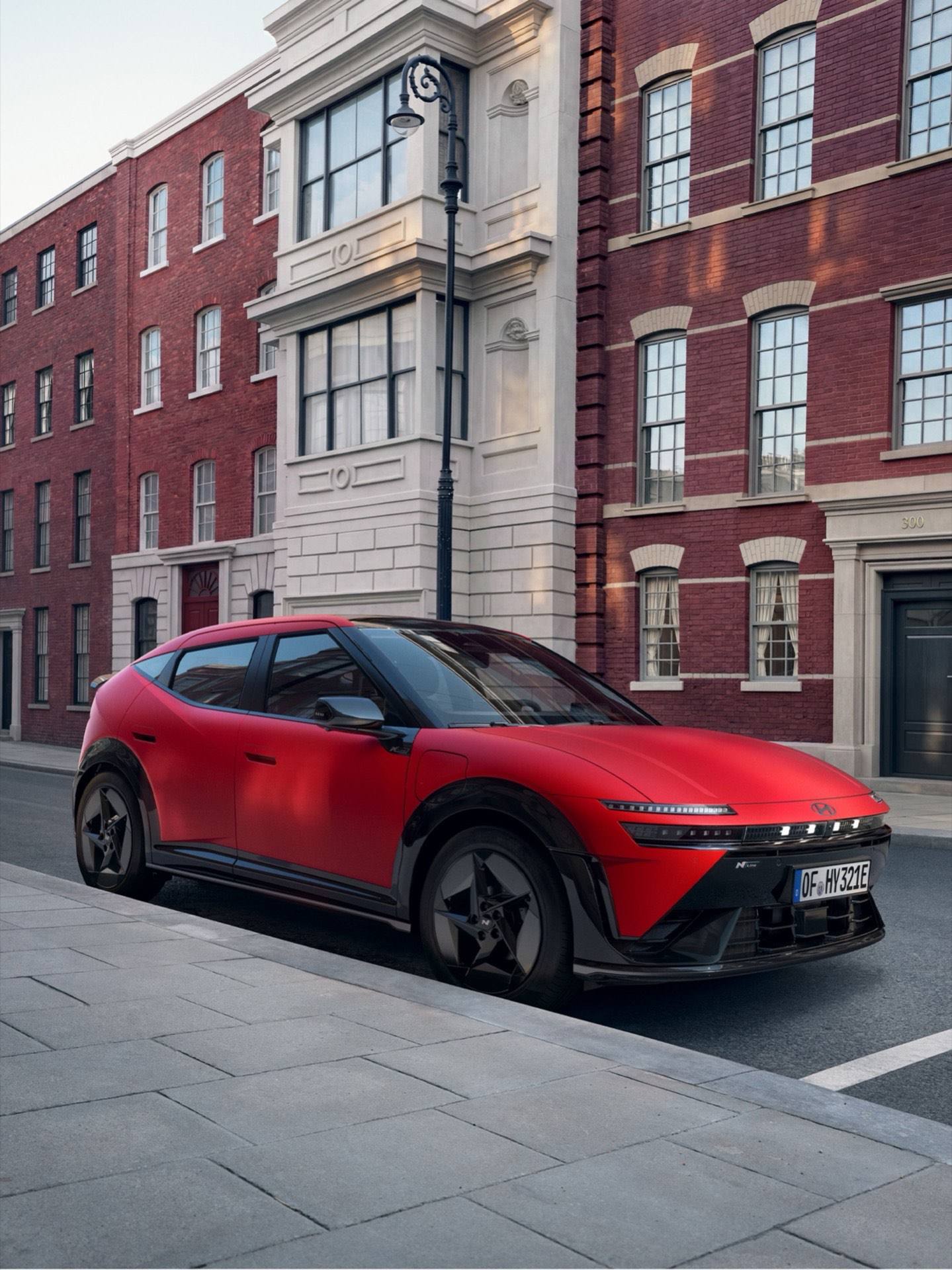 Red Hyundai IONIQ 3 N Line parked on a city street in front of attractive old buildings.