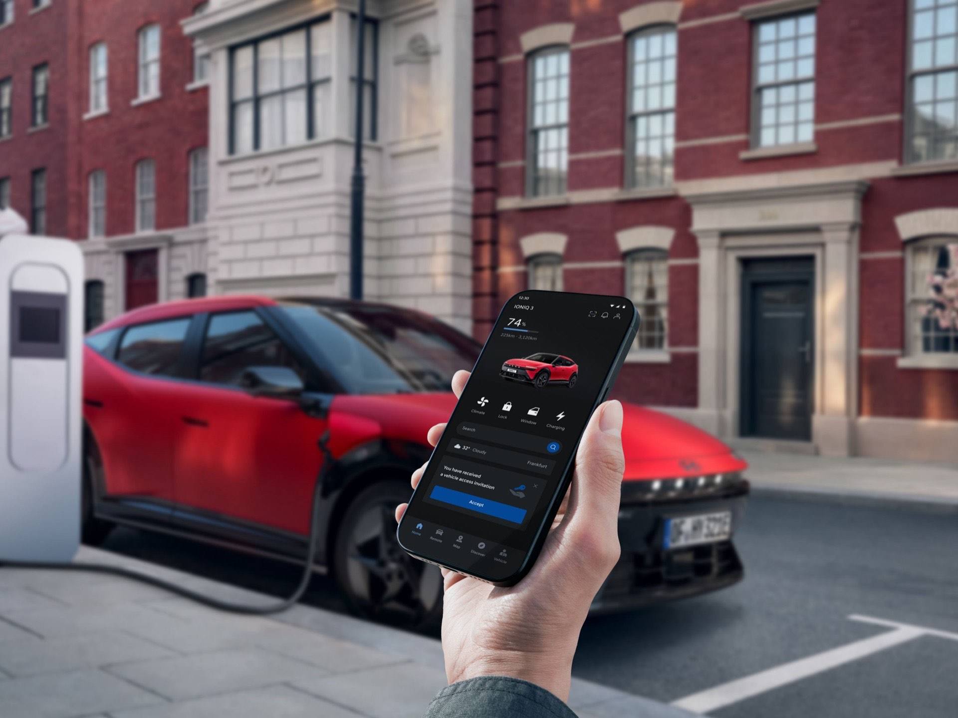 A hand holding a smartphone next to the Hyundai IONIQ 3 while it is plugged in to charge.