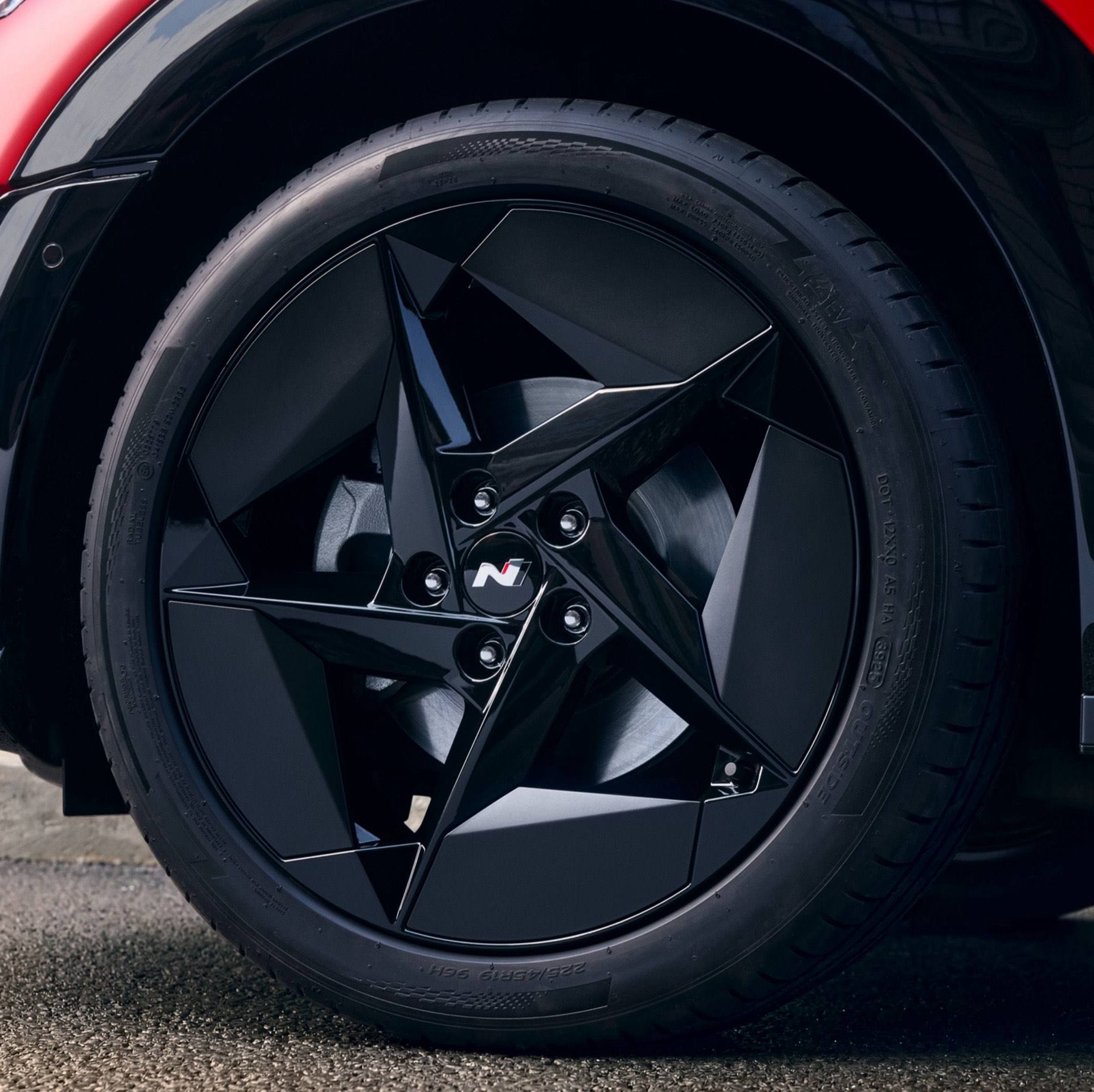 Wheel detail with black alloy rim featuring angular aero-inspired design.