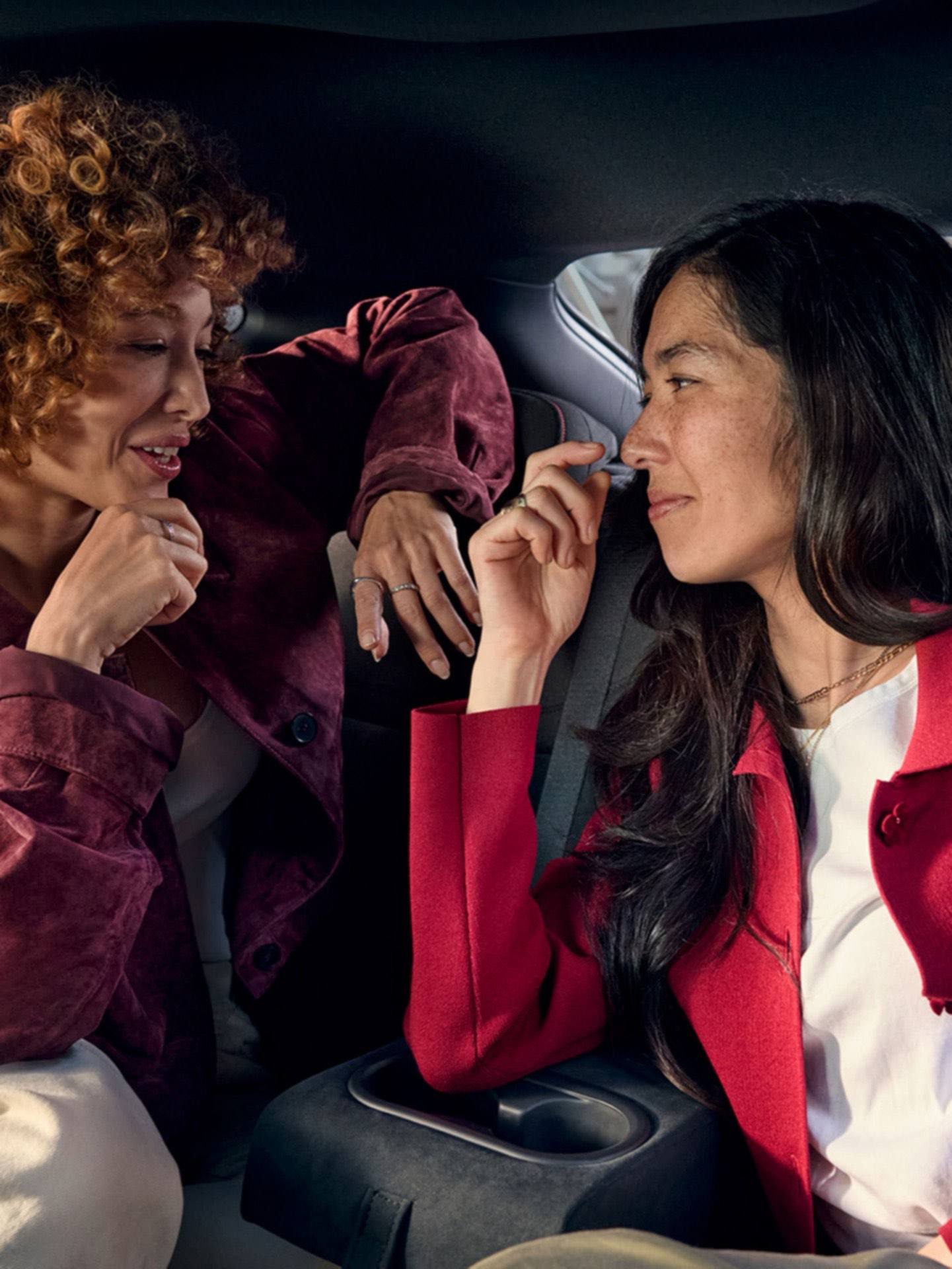 Two woman relaxing and talking in the rear seats of the Hyundai IONIQ 3.