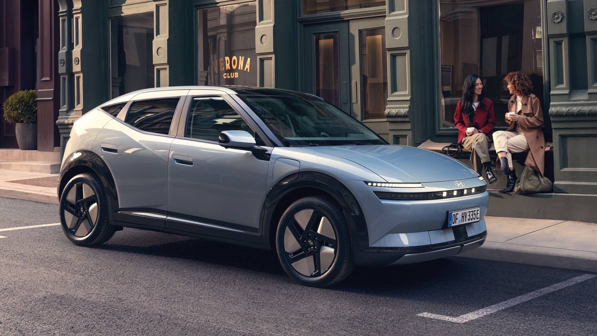 Hyundai IONIQ 3 EV parked on a city street with two woman sitting on a stoop next to it.