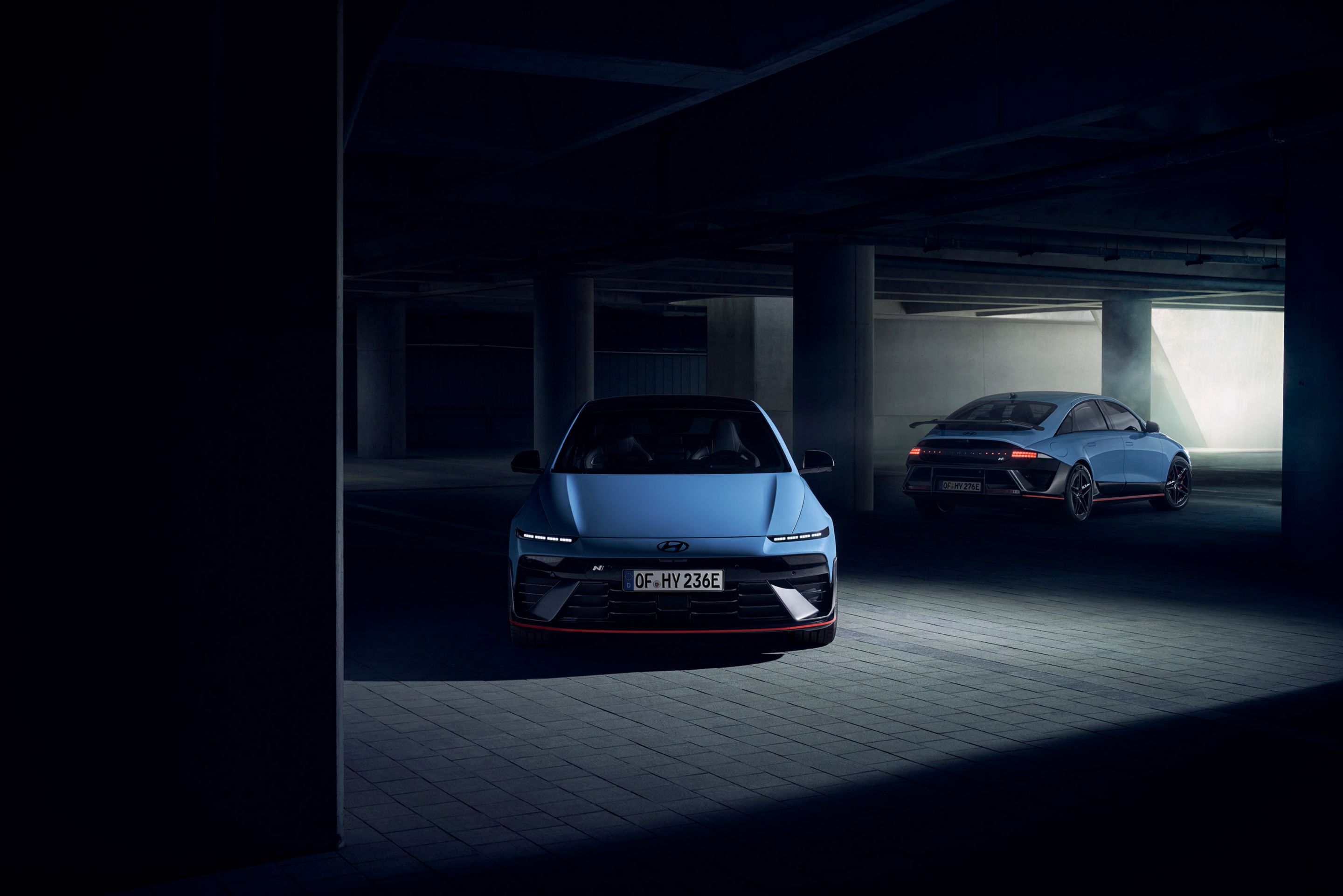 Two Hyundai IONIQ 6 N electric performance sedans in a dimly lit parking garage, front and rear view.